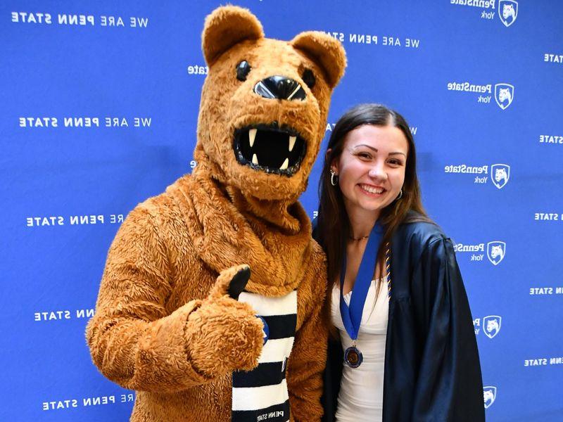 Female student standing next to the Nittany Lion mascot.