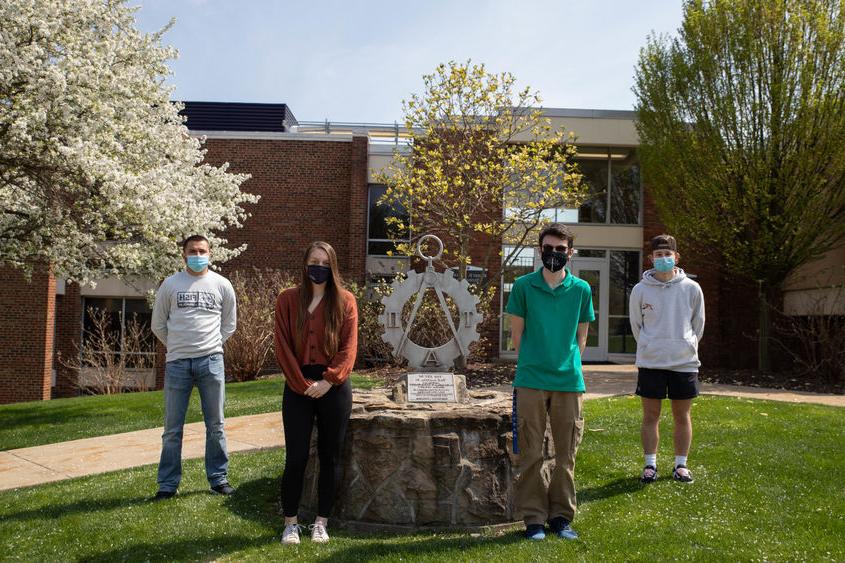 四个学生站在雕像旁边